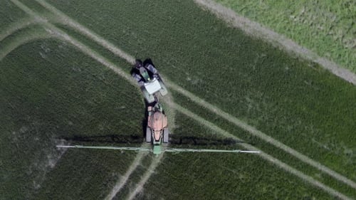 Tractor Spraying Crops in Green Field