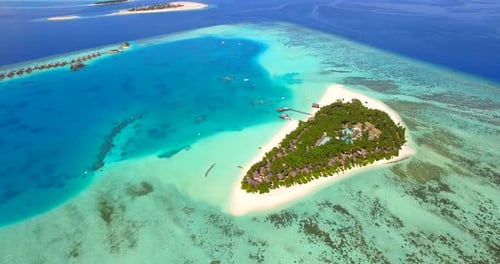 Aerial drone view of scenic tropical island and resort hotel with overwater bungalows in Maldives.