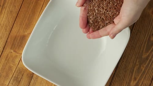 Las manos de las mujeres vierten semillas de lino en un plato