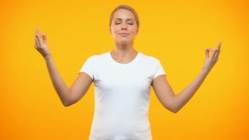 Woman Meditating with Mudra Against Orange Backdrop