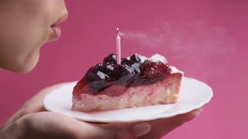 Woman Blows Out Candle on Cake Slice