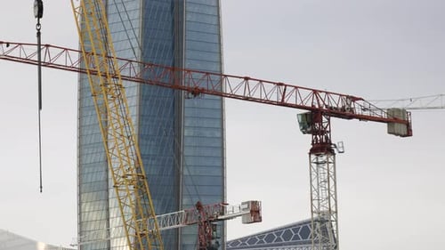 Hochkranarbeiten auf einer Baustelle mit einem gläsernen Gebäudeturm