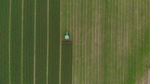 Aerial View of Tractor Tilling Crops in Green Field