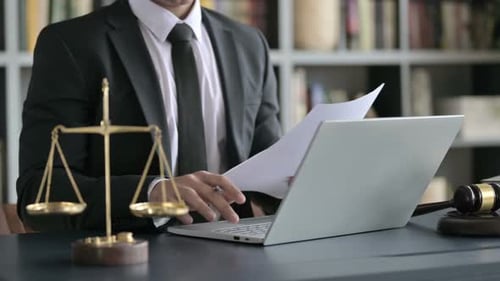 Close Up Shoot of Lawyer Hand Making Notes with Laptop in Court Room