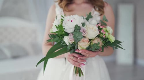 Bride Holding a Bouquet of Flowers in White Room
