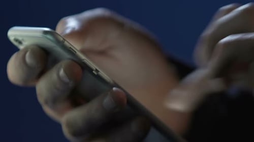 Hands Interacting With Smartphone at Night