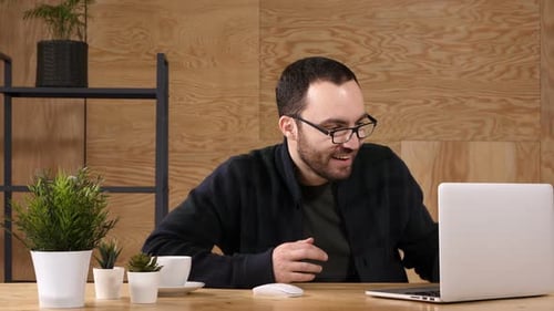 Guy in Front of a Monitor Laptop Watching Video and Reacts Emotionally