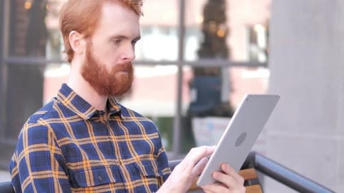 Bart Junger Mann benutzt Tablet beim Sitzen im Freien