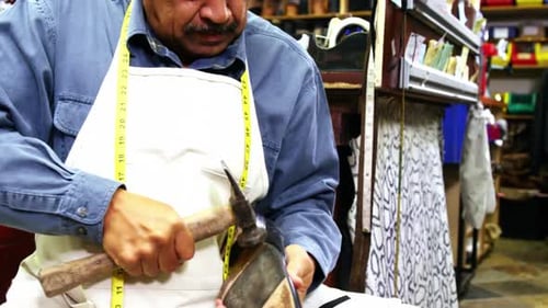 Craftsman Hammering Shoe Sole in Workshop