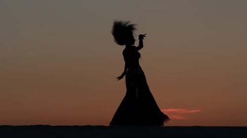 Belly Dancing Against the Beautiful Sunset on the Beach. Silhouettes