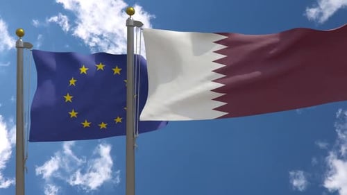 European Union and Qatar Flags Waving Against Blue Sky