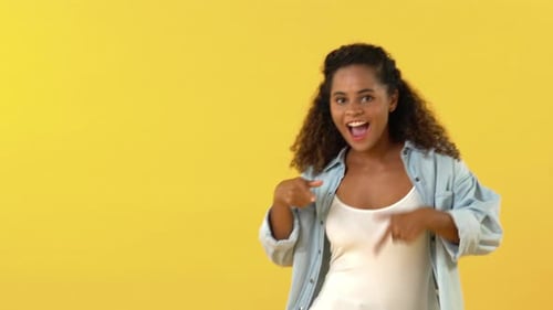 Woman Smiling and Gesturing on Yellow Background
