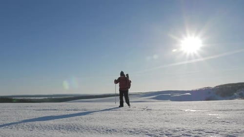 Winter Hiker Walking Across Snowy Plain