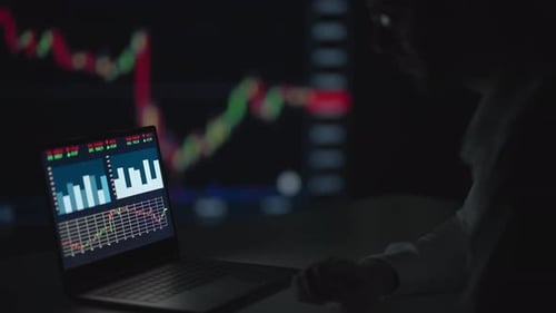 Young Adult Analyzing Stock Market Data at Night
