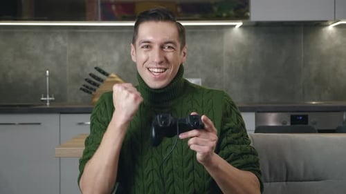 Enthusiastic young man playing video game at home