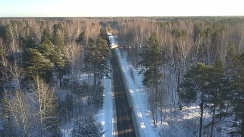 Aerial Motion Above Road with Running Man in Winter Forest