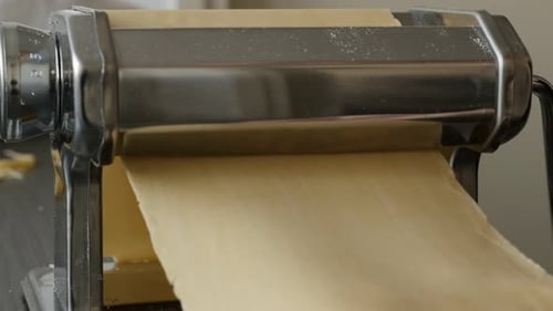 Pasta Dough Being Rolled Through Machine