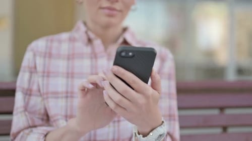 Close Up of Woman Using Smartphone While Sitting Outdoor