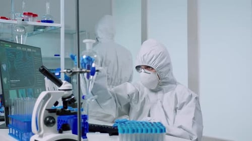 Ccientist with Coverall in Lab Performs Tests with Blue Liquid