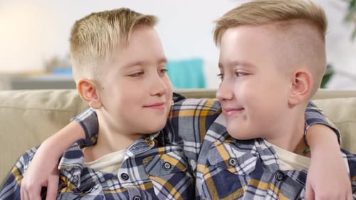Two Smiling Young Boys Sitting Together on Couch