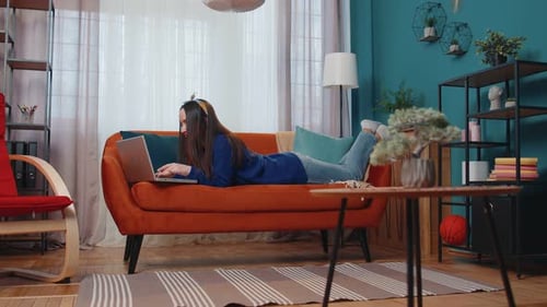 Woman Relaxes on Couch Using Laptop