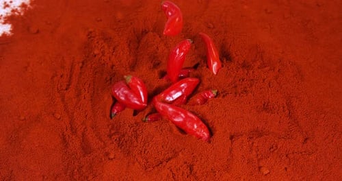 Falling Fresh Red Peppers into Powdered Chili