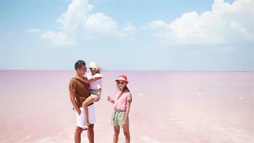 Family Walk on a Pink Salt Lake on a Sunny Summer Day.