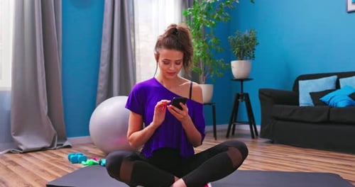 Woman Using Smartphone on Yoga Mat at Home