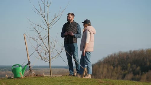 Ein paar Freiwillige diskutieren etwas, während sie neben einem gepflanzten Baum stehen