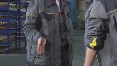 Cropped Shot of Two Female Workers Shaking Hands at the Factory Storage