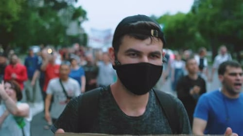 Man Wearing Mask Walks in a City Protest