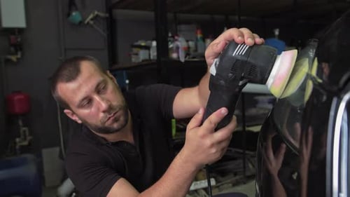 Man Polishing Car with Powered Buffer in Shop