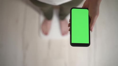Woman Holds Phone with Green Screen, Vertical Shot