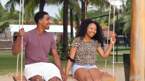 Romantic Couple on Tropical Beach Swing Holding Hands