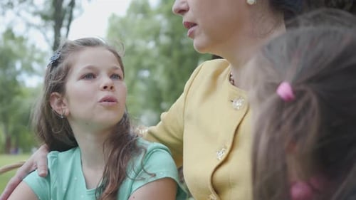 Child Listens to Woman Outdoors in Park
