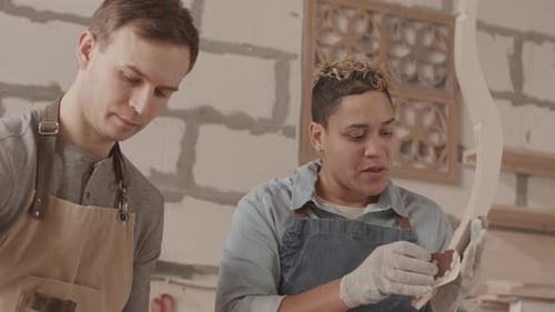 Woodworkers Sanding Intricate Wood Carving in Studio