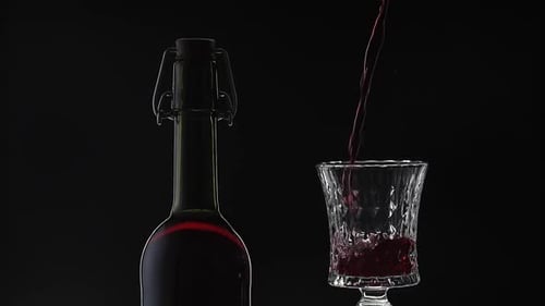 Rose Wine. Red Wine Pour in Wine Glass Over Black Background. Slow Motion