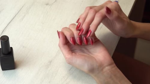 Hands Showcasing Manicured Nails with Shiny Red Polish
