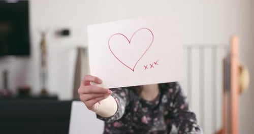 Girl Shows Heart Drawing in an Interior Setting
