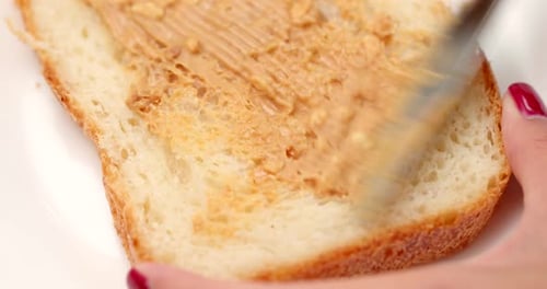 Spreading Chunky Peanut Butter on Slice of Bread
