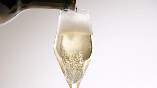 Champagne Flows From a Bottle Into a Beautiful Glass on White Background