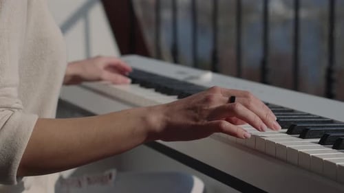 Woman Plays Piano Keyboard at Home During the Day