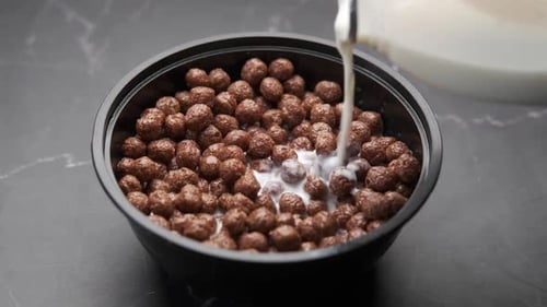 Pouring Milk Into Bowl of Chocolate Cereal