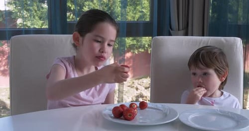 Children Eating Strawberries at Kitchen Table