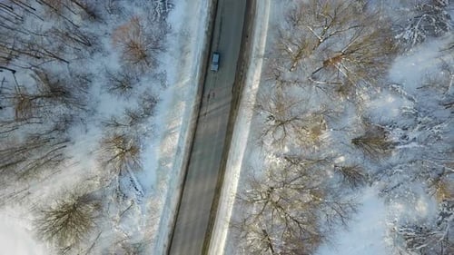 Car Driving Through a Snowy Winter Forest From Above