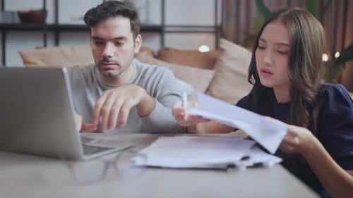 Couple Working Together At Home With Paperwork