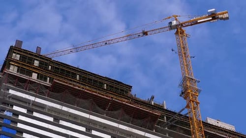Crane on a Construction Site Against the Blue Sky Is Building New Skyscraper. Building Construction.