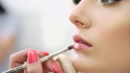 Maquiador Closeup aplicando cosméticos nos lábios da mulher