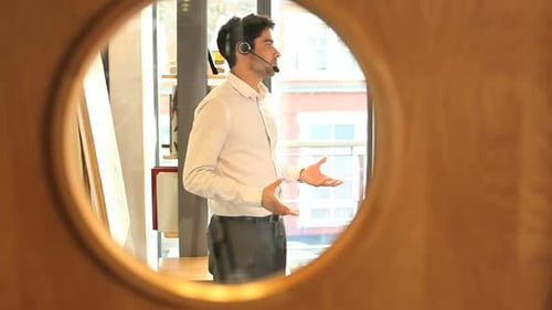 Businesss male talking on headset in office view trough office door window