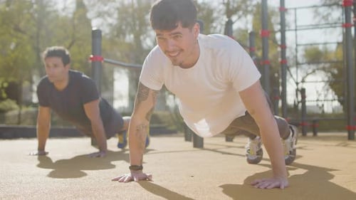 Athletic Men Doing Push Ups Together Outdoors